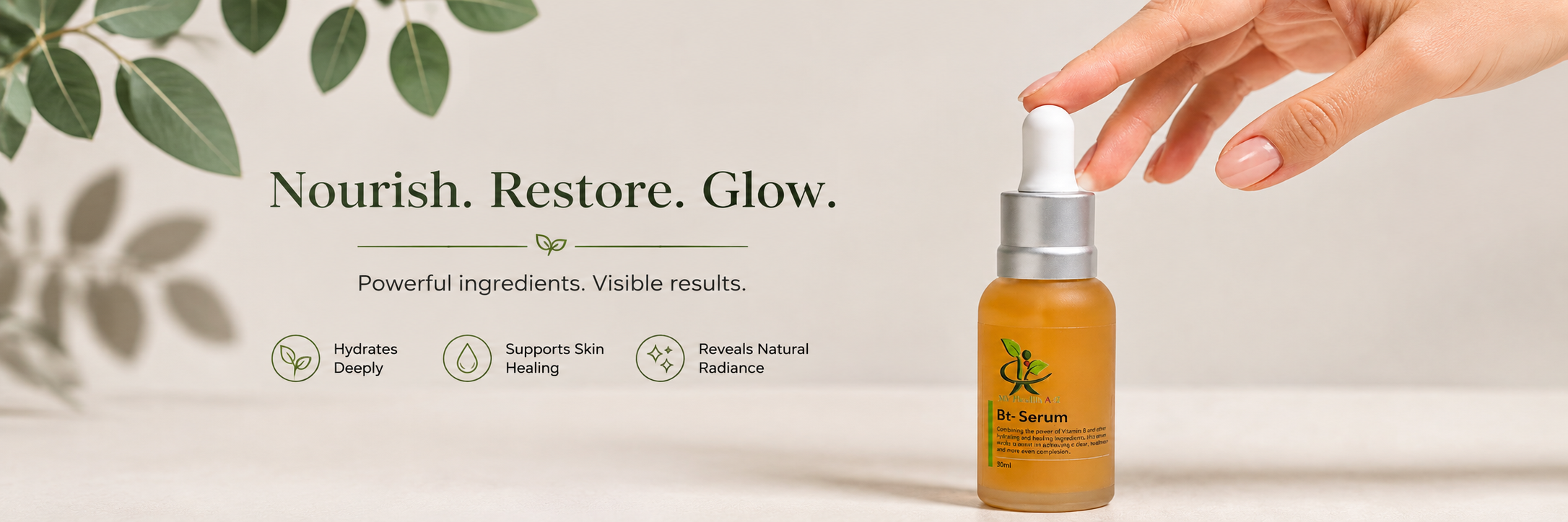 A hand with manicured nails is about to press the white dropper cap of a small amber glass bottle labelled 'B+-Serum'. The background is a clean, neutral off-white studio setting with soft, out-of-focus green leaves in the upper left corner.