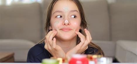 Teenager applying face cream with a smile