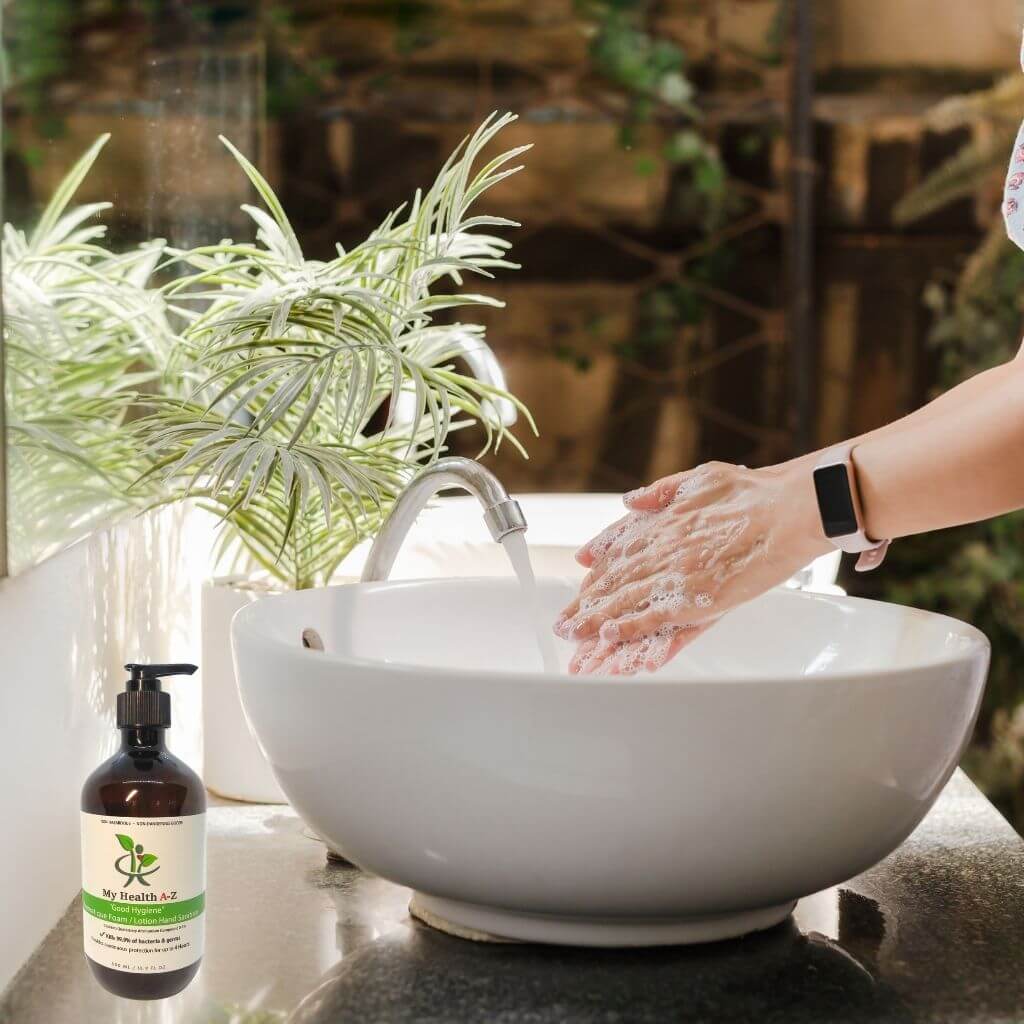 Person washing hands under a faucet with a bottle of soap next to a sink, surrounded by plants.