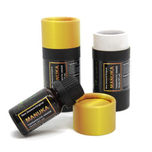 Load image into Gallery viewer, black cylinder with yellow lid in front a bottle of manuka essential oil resting on a yellow lit 
