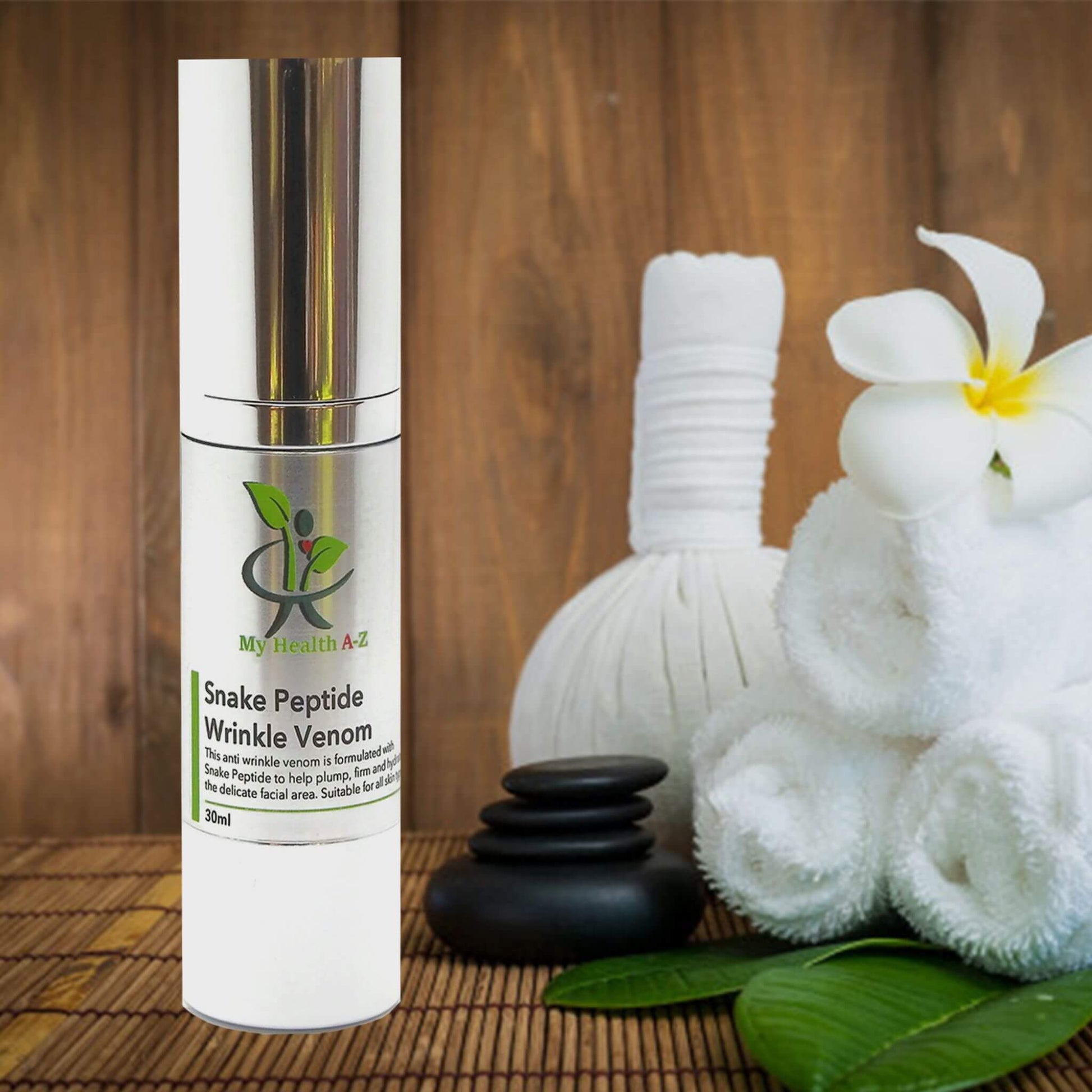 Snake Peptide Wrinkle Venom airless pump bottle next to some black stones and towels on a leaf
